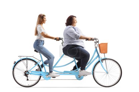Téléchargez les photos : Photo de profil pleine longueur d'une femme mince et corpulente chevauchant un vélo tandem isolé sur fond blanc - en image libre de droit