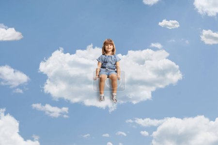 Photo for Little girl sitting on a cloud and smiling up in the sky - Royalty Free Image