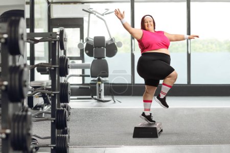 Foto de Alegre más tamaño mujer ejercicio paso aeróbicos en un gimnasio - Imagen libre de derechos