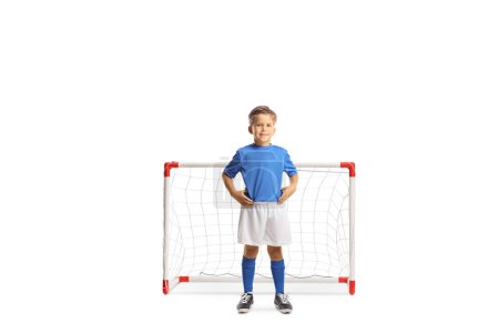 Photo for Full length portrait of a boy in a football kit posing in front of a mini goal isolated on white background - Royalty Free Image