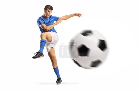 Foto de Joven futbolista pateando una pelota aislada sobre fondo blanco - Imagen libre de derechos