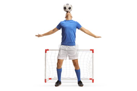 Foto de Jugador de fútbol sosteniendo una pelota con la cabeza delante de un mini gol aislado sobre fondo blanco - Imagen libre de derechos