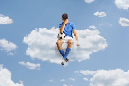 Foto de Triste jugador de fútbol sentado en una nube en el cielo - Imagen libre de derechos
