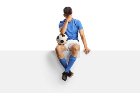 Foto de Jugador de fútbol decepcionado sentado en un panel en blanco aislado sobre fondo blanco - Imagen libre de derechos