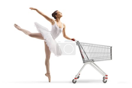 Photo for Full length profile shot of a ballerina in a white tutu dress dancing and holding a shopping cart isolated on white background - Royalty Free Image