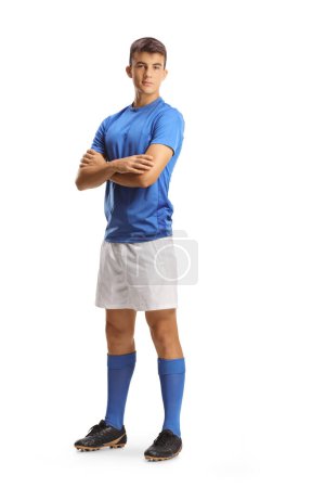 Foto de Retrato completo de un joven futbolista en un jersey azul posando con los brazos cruzados aislados sobre fondo blanco - Imagen libre de derechos