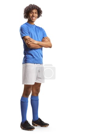 Foto de Retrato completo de un futbolista afroamericano en un jersey azul posando con los brazos cruzados aislados sobre fondo blanco - Imagen libre de derechos