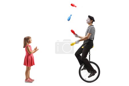 Téléchargez les photos : Profil pleine longueur prise d'une fille applaudissant et regardant un mime jongler et chevauchant un monocycle isolé sur fond blanc - en image libre de droit