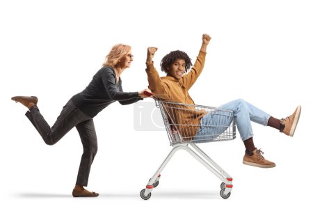 Foto de Mujer madura empujando a un joven afroamericano dentro de un carrito de compras aislado sobre fondo blanco - Imagen libre de derechos