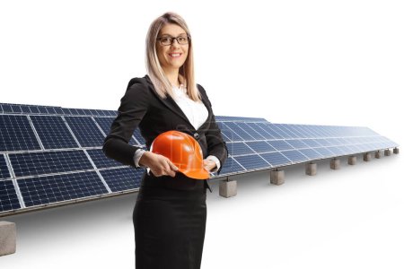 Foto de Empresaria sosteniendo un casco frente a paneles fotovoltaicos aislados sobre fondo azul - Imagen libre de derechos