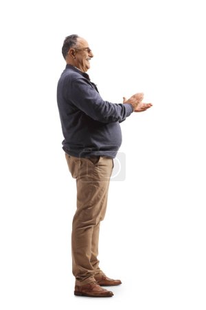 Téléchargez les photos : Plan de profil pleine longueur d'un homme mature heureux applaudissant avec les mains isolées sur fond blanc - en image libre de droit