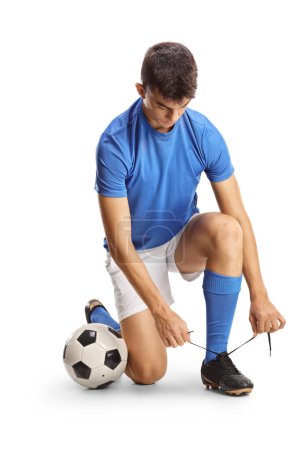 Foto de Largura completa de un futbolista arrodillado y atando tacos aislados sobre fondo blanco - Imagen libre de derechos
