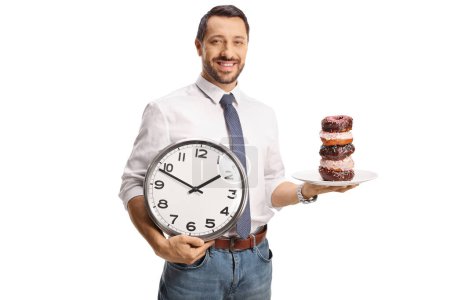 Foto de Hombre sonriente sosteniendo un plato con rosquillas y un reloj aislado sobre fondo blanco - Imagen libre de derechos