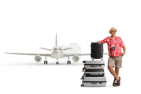 Téléchargez les photos : Homme mûr devant un avion appuyé sur des valises isolées sur fond blanc - en image libre de droit