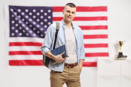 Photo for Male student with backpack and books with a USA flag in the background - Royalty Free Image