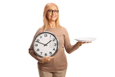 Téléchargez les photos : Femme tenant une assiette et une horloge isolées sur fond blanc - en image libre de droit
