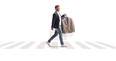 Photo for Man carrying suit with a plastic dry cleaning bag and crossing a street isolated on a white background - Royalty Free Image