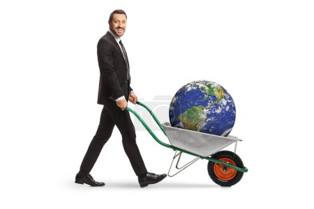 Téléchargez les photos : Homme d'affaires poussant une brouette avec la terre végétale à l'intérieur isolé sur fond blanc - en image libre de droit