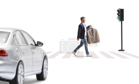 Foto de Hombre llevando traje con una bolsa de plástico de limpieza en seco y cruzando una calle mientras el coche espera en el paso de peatones aislado sobre un fondo blanco - Imagen libre de derechos