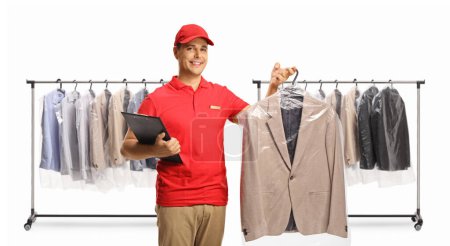 Photo for Dry cleaning worker holding a suit and a clipboard in front of clothing racks isolated on a white backgroun - Royalty Free Image