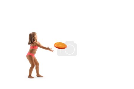 Téléchargez les photos : Petite fille en bikini jouant avec un disque volant isolé sur fond blanc - en image libre de droit