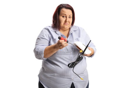 Foto de Mujer confusa tratando de arreglar el router con un destornillador aislado sobre fondo blanco - Imagen libre de derechos