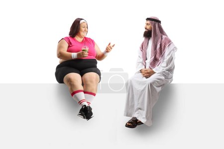 Photo for Corpulent woman in sportswear sitting on a panel and talking to a saudi arab man isolated on white background - Royalty Free Image