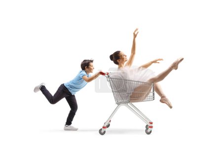 Foto de Niño empujando una bailarina dentro de un carrito de compras aislado sobre fondo blanco - Imagen libre de derechos