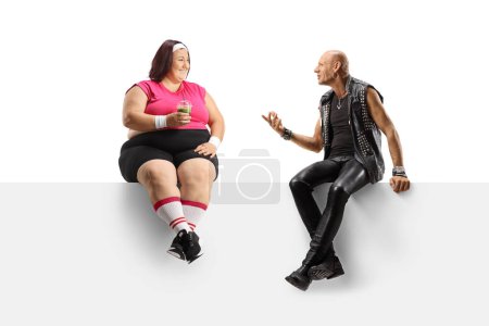 Photo for Punk talking to a young corpulent in sportswear lady and sitting on a panel isolated on white background - Royalty Free Image