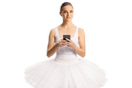 Foto de Bailarina en un vestido blanco sosteniendo un smartphone y mirando a la cámara aislada sobre fondo blanco - Imagen libre de derechos