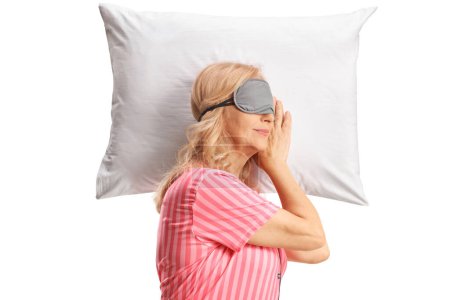 Foto de Mujer madura en pijama durmiendo con una máscara sobre una almohada aislada sobre fondo blanco - Imagen libre de derechos