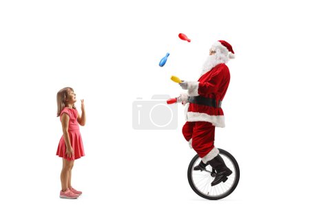 Photo for Little girl watching santa claus man riding a unicycle and juggling isolated on white backgroun - Royalty Free Image