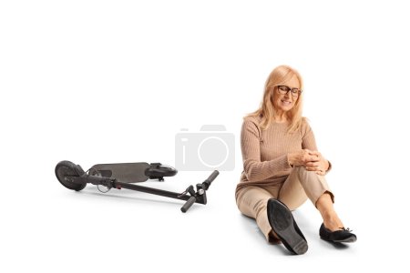 Téléchargez les photos : Femme avec scooter électrique tenant jambe blessée isolé sur fond blanc - en image libre de droit