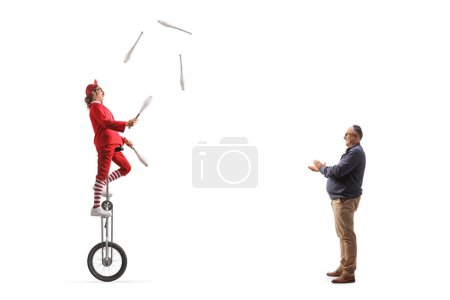 Téléchargez les photos : Homme mûr applaudissant un acrobate chevauchant une girafe monocycle et jonglant isolé sur fond blanc - en image libre de droit
