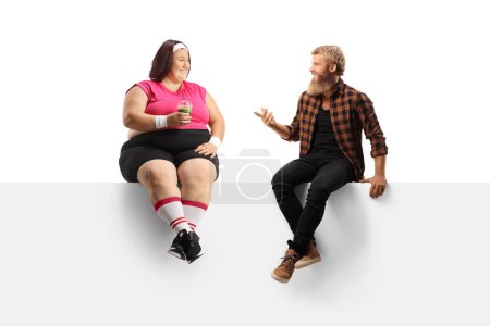 Foto de Tipo barbudo hablando con una mujer de talla grande en ropa deportiva sentado en un panel aislado sobre fondo blanco - Imagen libre de derechos