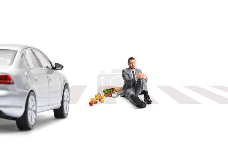 Téléchargez les photos : Un homme d'affaires percuté par une voiture assise à un passage à niveau isolé sur fond blanc - en image libre de droit
