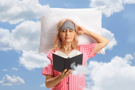 Téléchargez les photos : Femme reposant sur un oreiller dans les nuages et lisant un livre - en image libre de droit