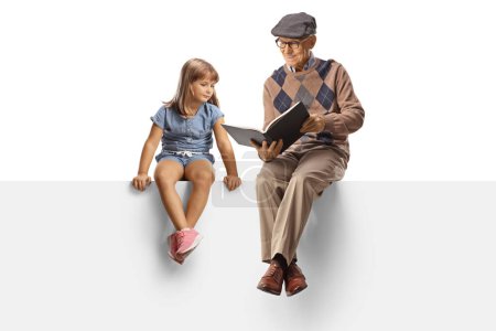 Foto de Anciano leyendo un libro a una niña y sentado en un panel en blanco aislado sobre fondo blanco - Imagen libre de derechos