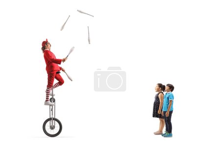 Téléchargez les photos : Les enfants regardent un acrobate monter une girafe monocycle et jongler isolé sur fond blanc - en image libre de droit