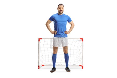 Foto de Retrato completo de un futbolista en top azul y pantalón corto blanco frente a un mini gol aislado sobre fondo blanco - Imagen libre de derechos