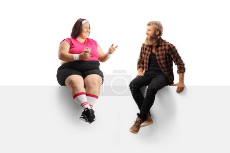 Téléchargez les photos : Femme de taille plus en tenue de sport tenant un shake vert sain et parlant à un gars barbu isolé sur fond blanc - en image libre de droit