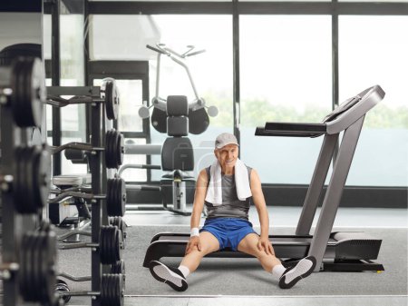 Photo for Tired elderly man sitting on a treadmill at the gym and smiling - Royalty Free Image