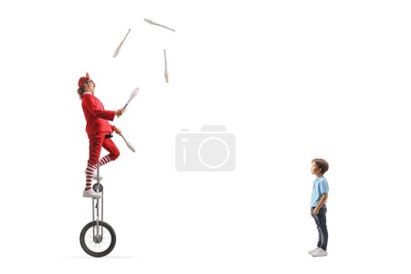 Photo for Little boy watching an acrobat riding a giraffe unicycle and juggling isolated on white background - Royalty Free Image