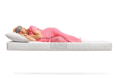 Foto de Mujer en pijama durmiendo con una máscara sobre un colchón flotante aislado sobre fondo blanco - Imagen libre de derechos