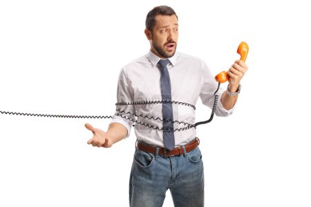 Téléchargez les photos : Homme enchevêtré dans un câble d'un téléphone rotatif vintage isolé sur fond blanc - en image libre de droit