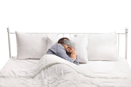 Foto de Hombre usando una máscara y durmiendo solo en una cama doble aislado sobre fondo blanco - Imagen libre de derechos