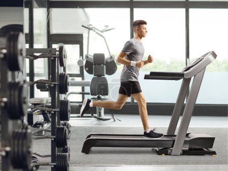 Profilbild in voller Länge von einem Mann, der in einem Fitnessstudio auf einem Laufband trainiert