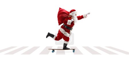 Photo for Full length profile shot of Santa Claus riding a longboard at a pedestrian crossing isolated on white background - Royalty Free Image