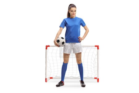 Foto de Retrato completo de una futbolista femenina con una pelota frente a un mini gol aislado sobre fondo blanco - Imagen libre de derechos