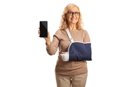 Téléchargez les photos : Femme avec une blessure au bras portant une fronde et montrant un smartphone isolé sur fond blanc - en image libre de droit